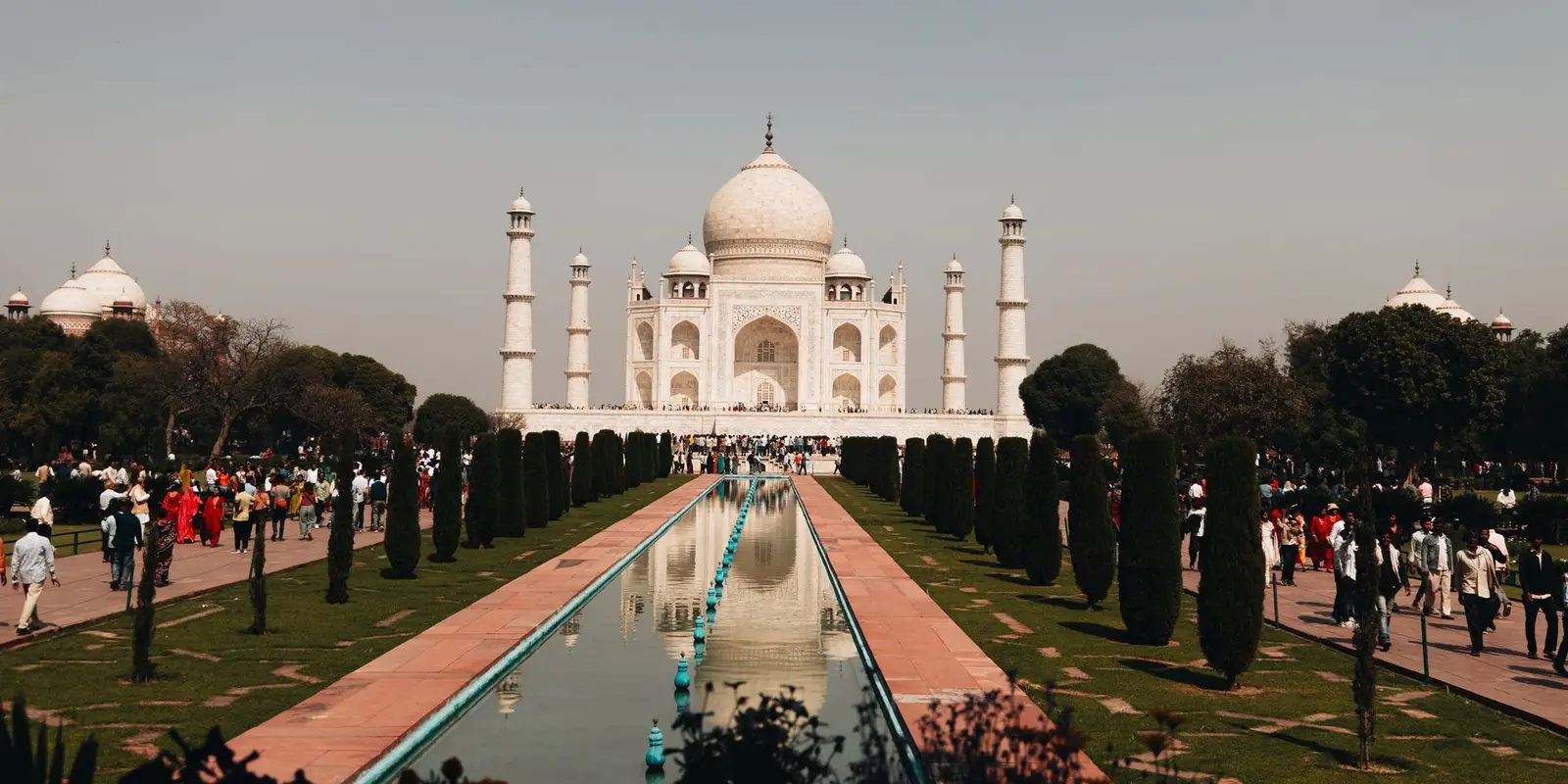 A beautiful view of the Taj Mahal with tourists and reflection in Agra, India.