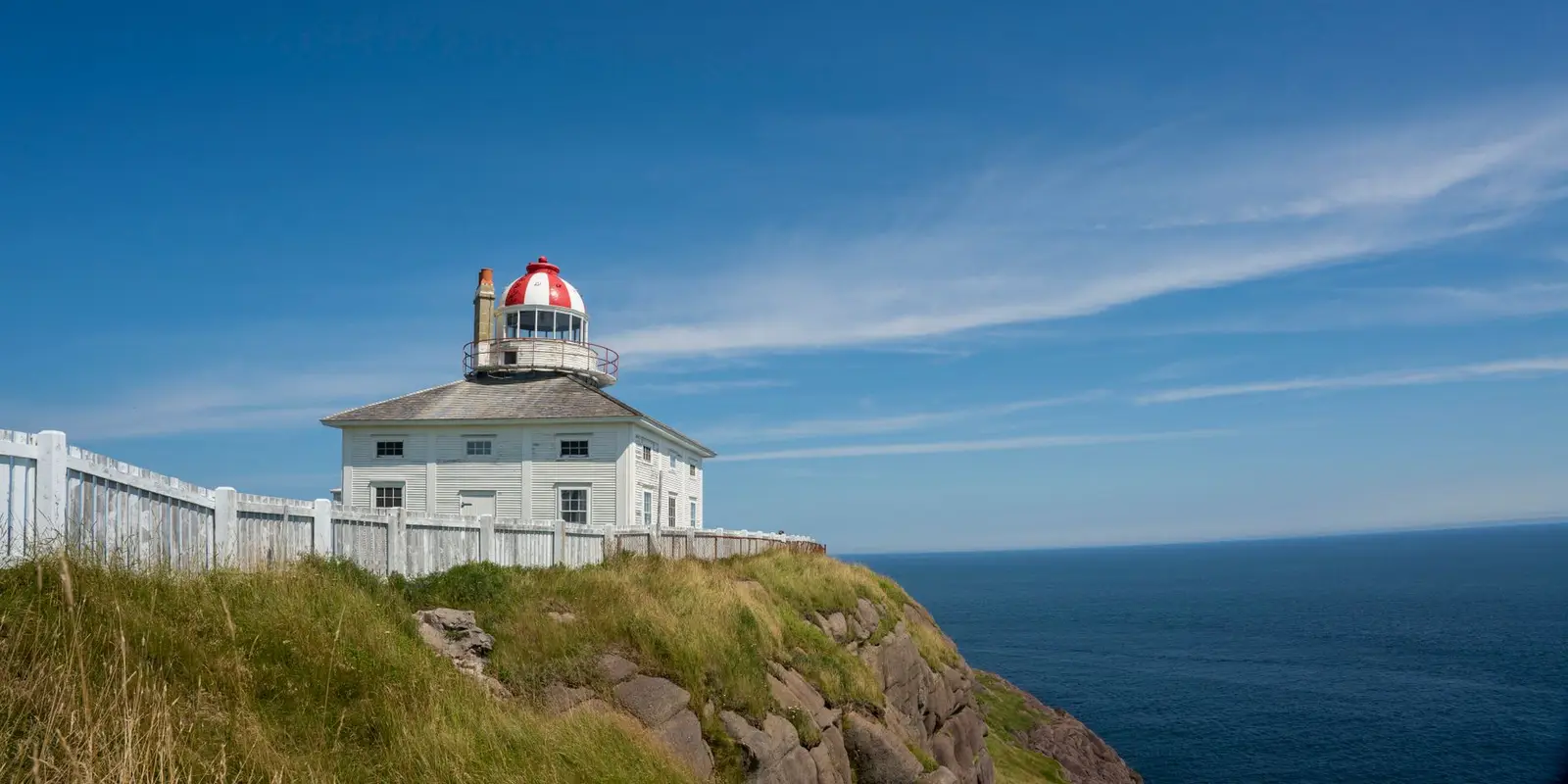 Beautiful view of Cape Spear lighthouse on a sunny day overlooking the ocean coast in Canada.