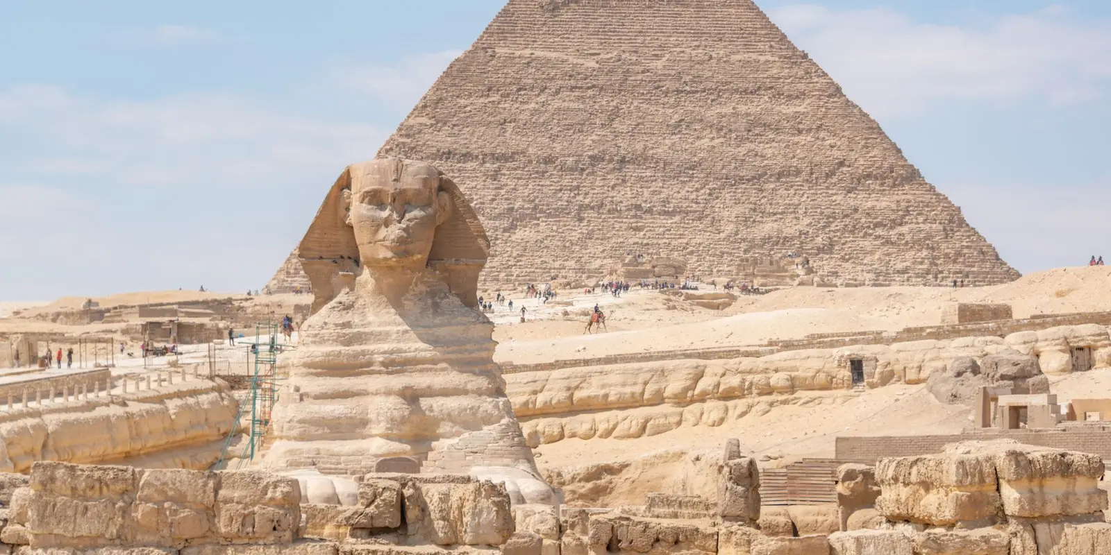 Iconic Great Sphinx and Pyramid of Khafre under a bright daytime sky in Giza, Egypt.
