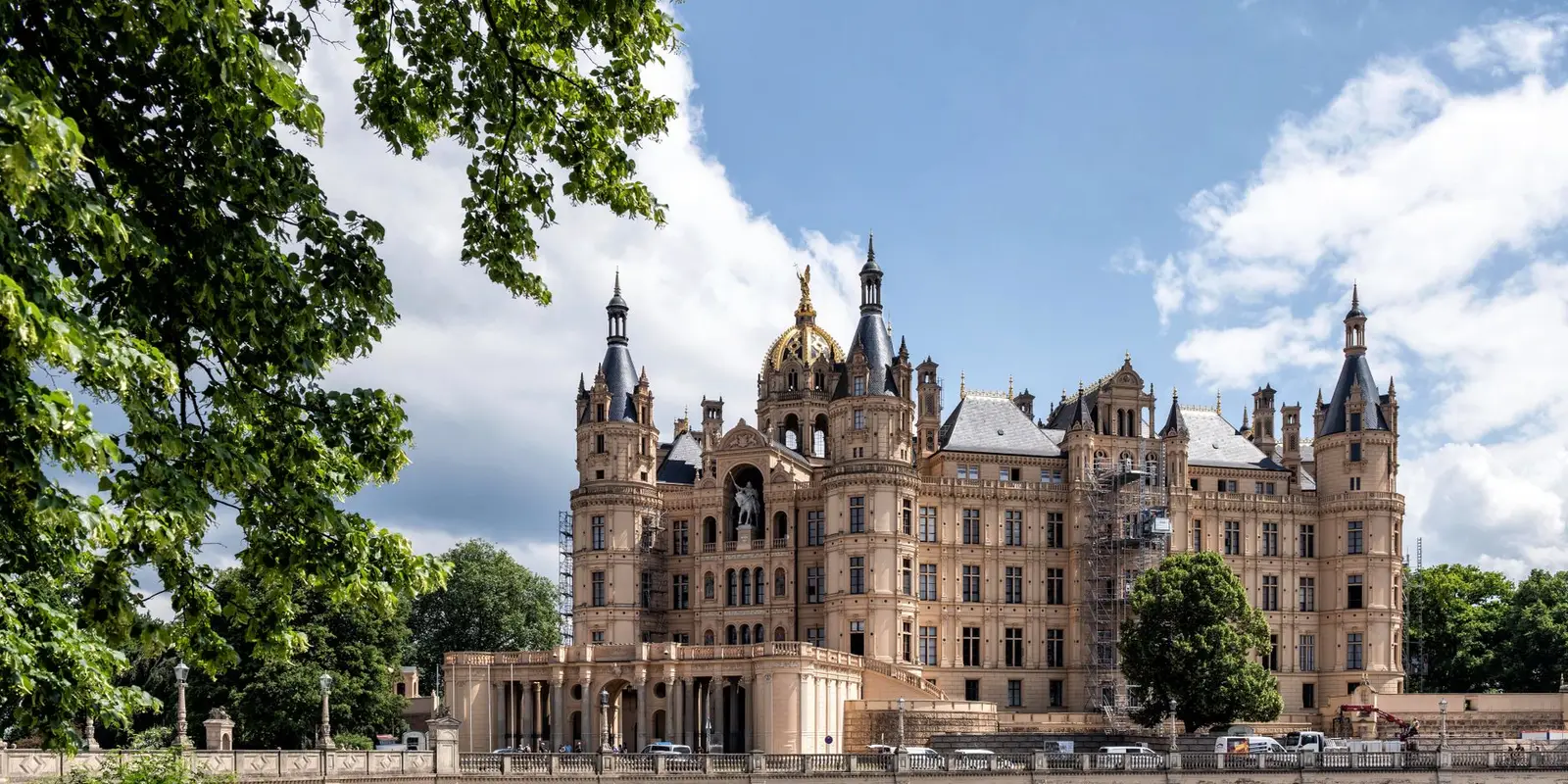 Stunning view of Schwerin Castle in Germany surrounded by lush greenery and reflecting lake.
