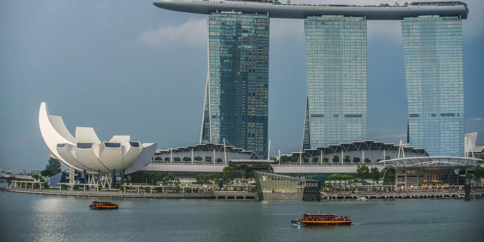View of Marina Bay Sands and ArtScience Museum in Singapore's skyline with a boat on the bay.