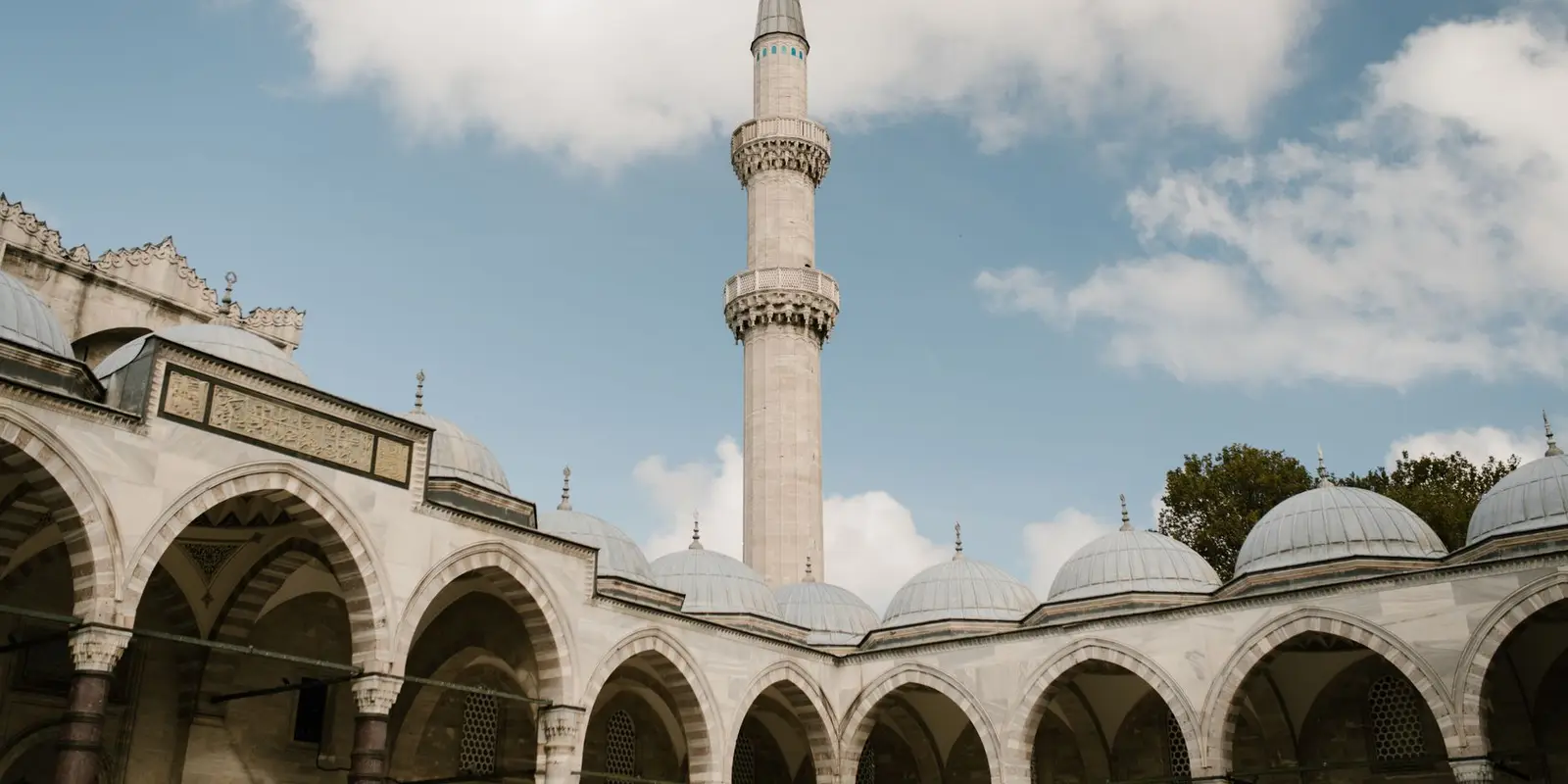 A stunning view of a mosque minaret and arches under a blue sky in Istanbul, Turkey.