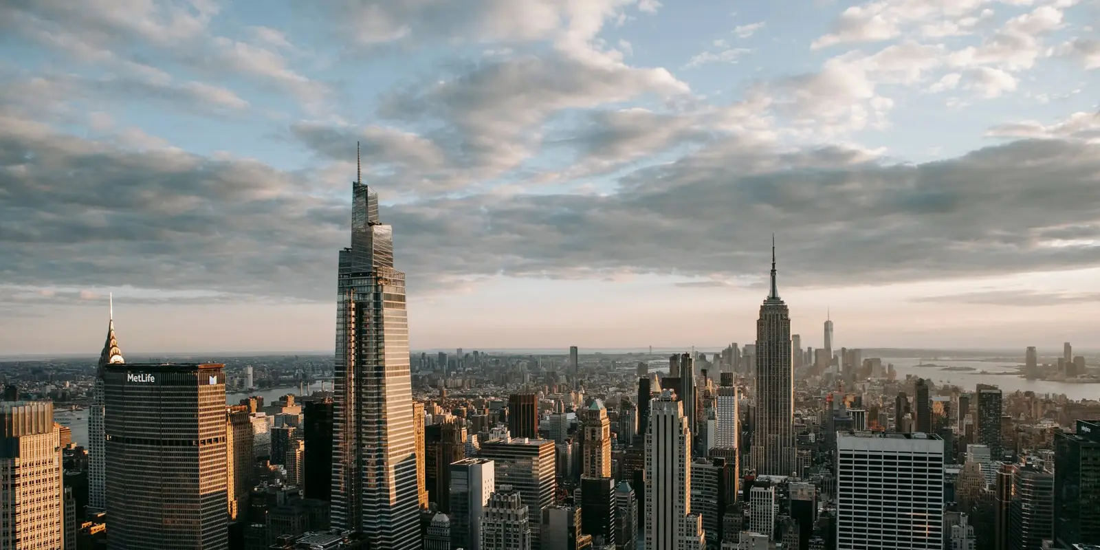 Multistage building facades with spires against ocean under cloudy sky in United States of America